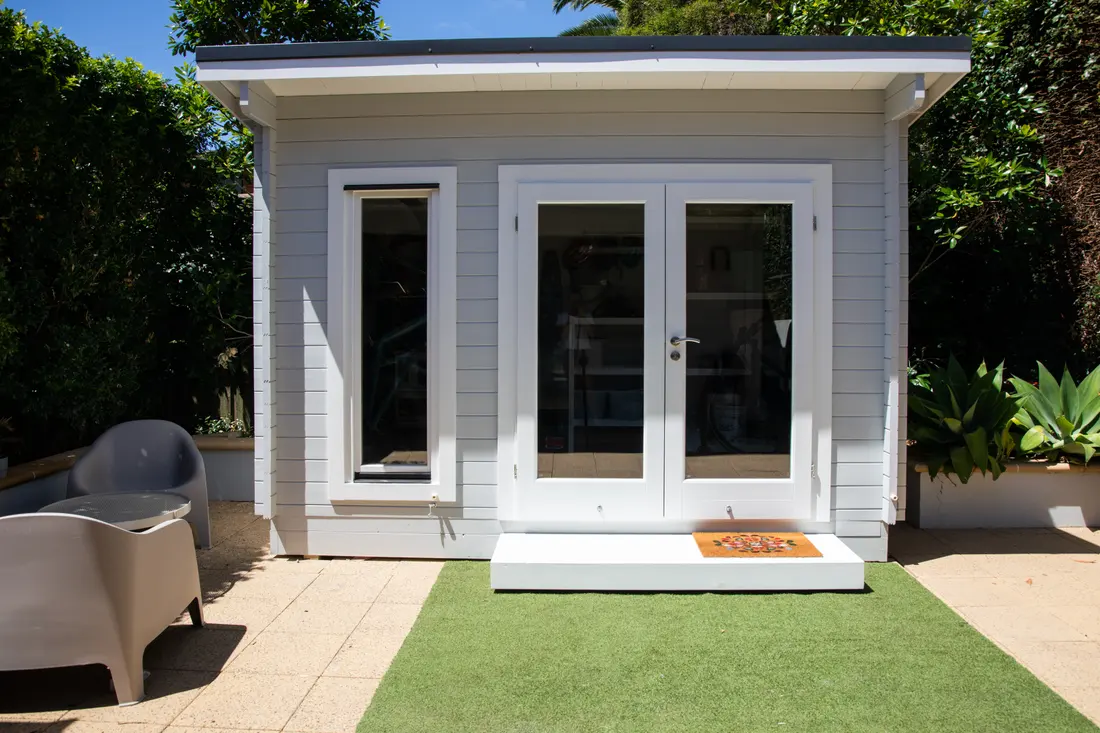 A garden room with glazed double doors at the end of a garden