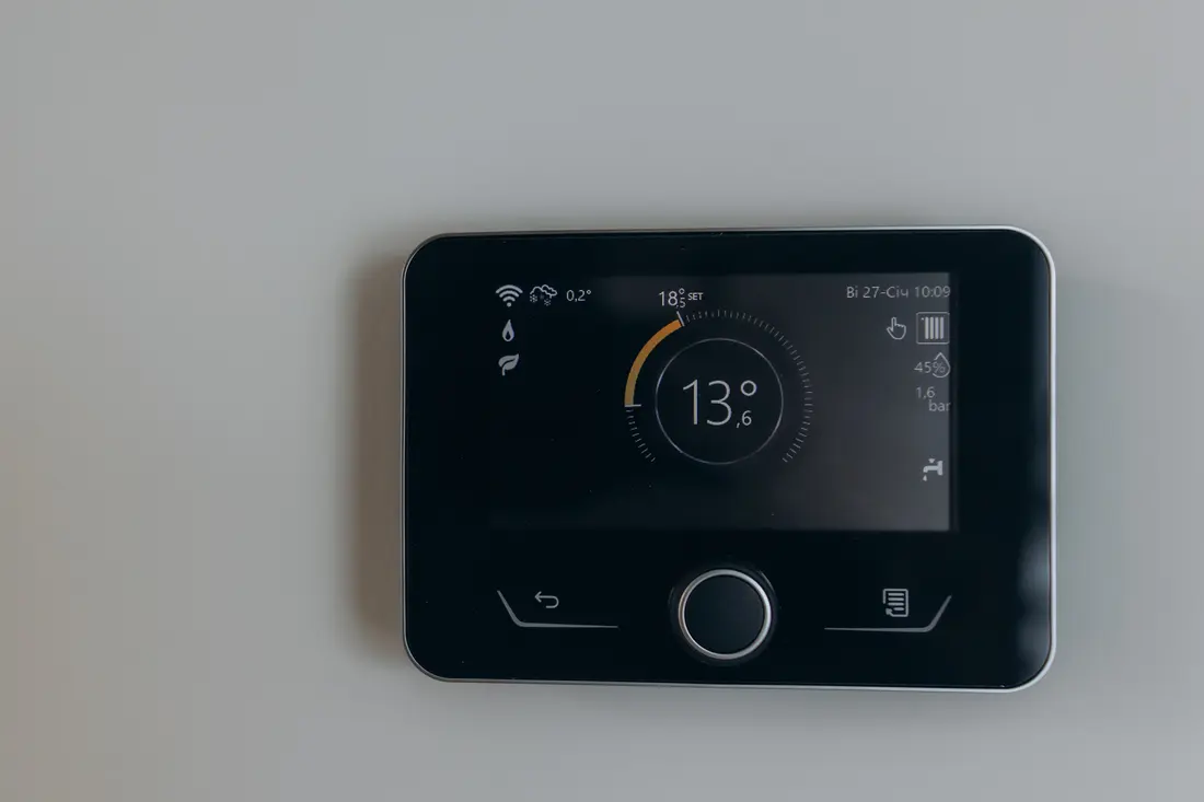 A wall-mounted heating controller showing a room temperature of 13 degrees
