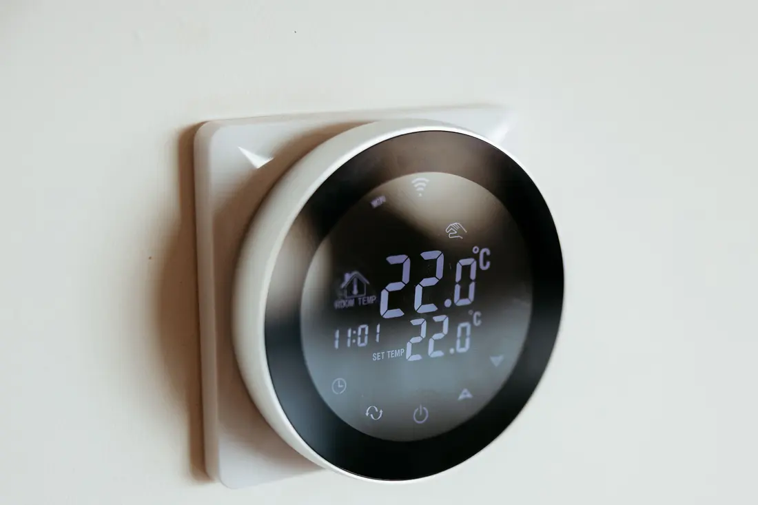A round digital room thermostat set to 22 degrees